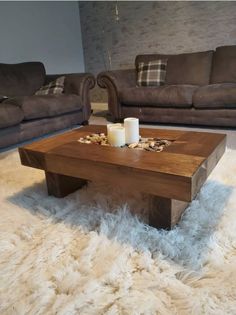 a wooden table sitting on top of a fluffy white rug in front of two couches