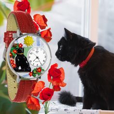 a black cat sitting next to a clock with cats on it's face and flowers in the background