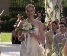 a woman in a wedding dress walking down the aisle with her bouquet on her hand