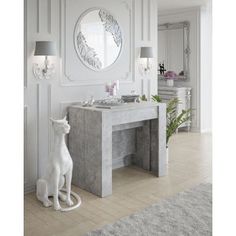 a white table with a mirror on the wall and a cat statue in front of it