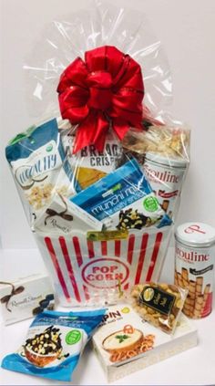 a basket filled with snacks and treats on top of a white table next to a red bow