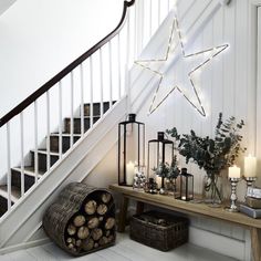 a star is hanging on the wall next to some candles and other decorations in front of a staircase