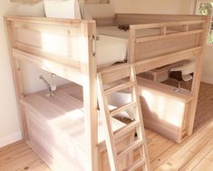 a wooden bunk bed sitting on top of a hard wood floor next to a window