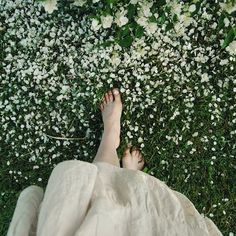 a person laying in the grass with their feet up and white flowers all around them