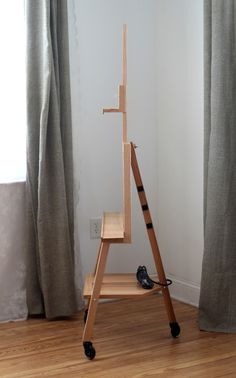 a wooden easel sitting on top of a hard wood floor next to a window