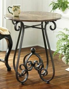 a wooden table with metal legs and a cup on it next to a potted plant