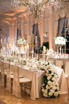 a long table is set up with white flowers and candles for an elegant wedding reception