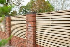 a brick wall with a wooden slatted fence on the top and bottom part