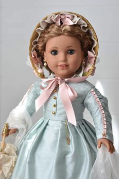 the doll is wearing a blue dress and bonnet