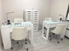 a white desk with two chairs and a mirror in a room that has drawers on the wall