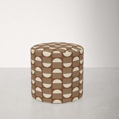 a brown and white patterned stool sitting on top of a table next to a wall