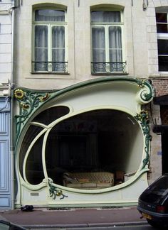 a car is parked in front of a building with an arched window on the side