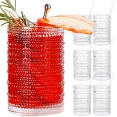 a red glass cup filled with lots of glasses and an apple slice on top of it