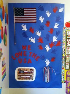 we love the usa bulletin board with handprints on it and american flags in the background