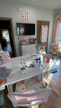 a sewing machine sitting on top of a white table next to a chair and tv