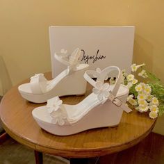 a pair of white shoes sitting on top of a wooden table next to a bouquet of flowers