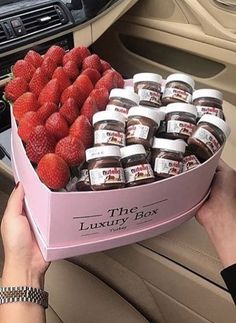 a pink box filled with jams and strawberries on top of a car dash board