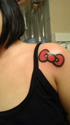 a woman with a tattoo on her shoulder that has a red and black bow in it