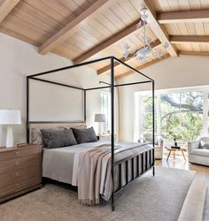 a bedroom with a four post bed and white walls