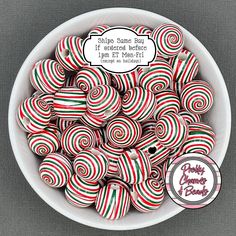 a white bowl filled with red and green striped lollipops on top of a table