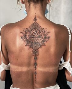 the back of a woman's neck with a lotus tattoo on it