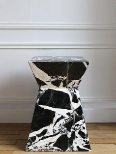 a black and white marble pedestal sitting on top of a hard wood floor next to a wall