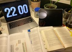 an open laptop computer sitting on top of a desk next to books and plant pots