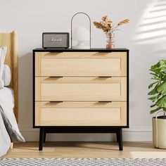 a wooden dresser sitting next to a bed with a plant on top of it in a bedroom