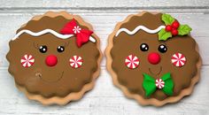 two decorated cookies sitting next to each other on top of a white wooden surface with candy canes