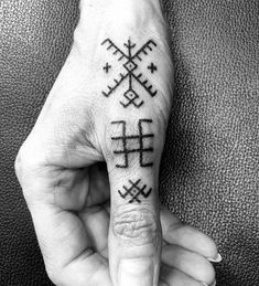 a person's hand with a small tattoo on the middle finger and two crosses