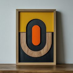 an orange and black object in a wooden frame on a shelf next to a white wall