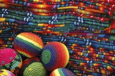 colorful crocheted balls sitting on top of each other in front of many different colored fabrics