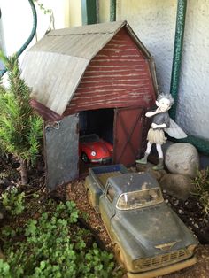 a toy car is parked in front of a shed with a tin man next to it