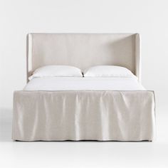 a bed with white sheets and pillows on it