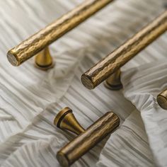 three brass handles on a bed with white sheets