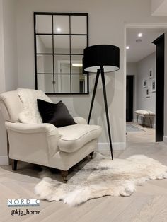 a white chair sitting on top of a hard wood floor next to a mirror in a living room