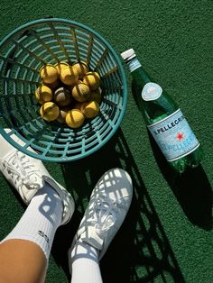 a person's feet next to a basket of lemons and a bottle of water