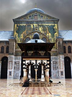 a large building with an ornate design on it's front wall and two men sitting at the alter