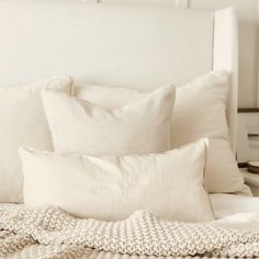 a white bed topped with lots of pillows