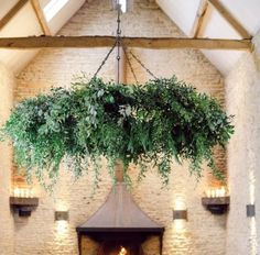 an indoor fireplace with greenery hanging from the ceiling