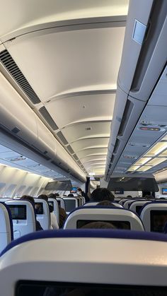 the inside of an airplane with rows of seats and overhead lighting on each side of the aisle