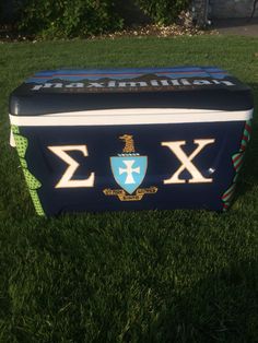 an ice chest sitting in the grass on top of some green grass with a blue and white design