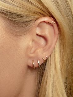 a woman wearing gold ear cuffs with two small rings on her left and right ear