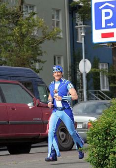 a man in blue and white running down the street with a parking sign behind him