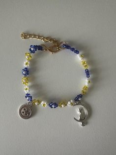 a beaded bracelet with a button on it and a charm hanging from the clasp