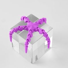 a purple plastic spider sitting on top of a white box