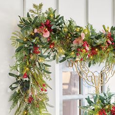 two christmas wreaths hanging from the side of a door decorated with greenery and lights