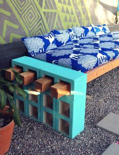 a bed made out of wooden blocks sitting on top of gravel next to a potted plant