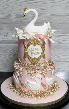 there is a pink cake with swans on it and gold trimmings around the edges