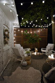 an outdoor living area with white furniture and string lights